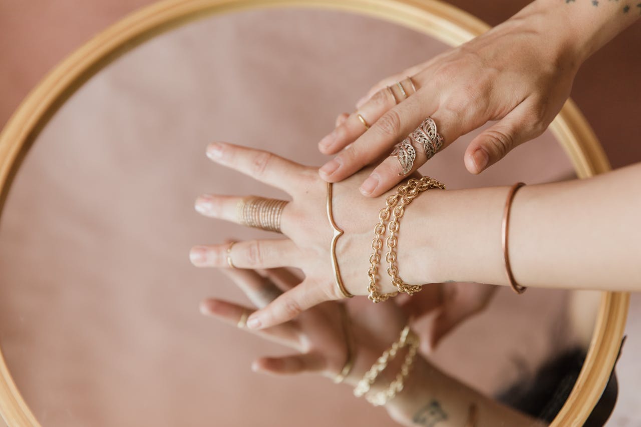 Close-up of elegant hands with jewelry, reflecting on a mirror surface.